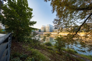 Wroclaw, Polonya - 30 Ağustos 2024: Bereketli ağaçlar ve nehir kenarındaki yeşillikler tarafından çerçevelenmiş güneşli Wroclaw şehri, aydınlık bir günde kentsel güzelliği yakalıyor