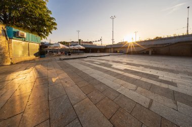 Wroclaw, Polonya - 30 Ağustos 2024: Güneşli, güneşli bir meydan, sakin şehir hendeğinin yanındaki merdivenlerden inen, gün batımının ılık renklerinde yıkanan