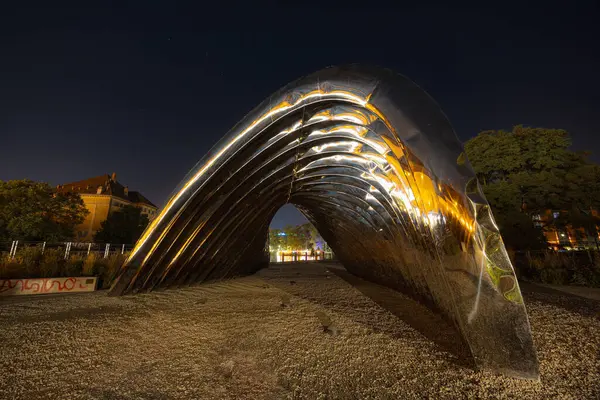 Wroclaw, Polonya - 24 Ağustos 2024: Wroclaw 'daki Daliowa Adası' nda gece aydınlatılmış Nawa heykeli, yıldızlı bir gökyüzü altında şehir ışıklarını yansıtan modern bir sanat kurulumu