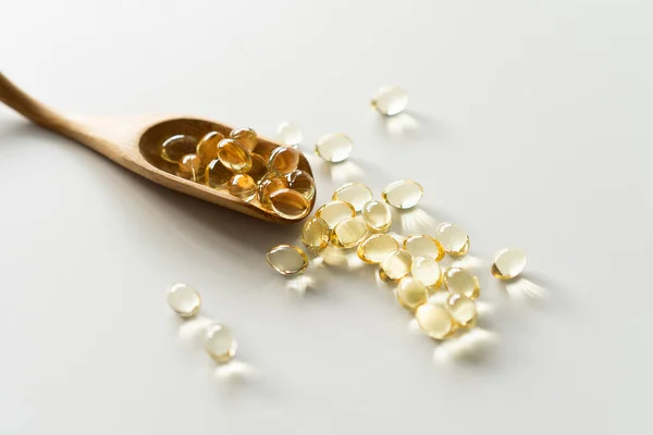 Vitamins on a white background. Capsules on spoon suitable for: fish oil, omega 3, omega 6, omega 9, vitamin A, vitamin D, vitamin D3, vitamin E. Health concept