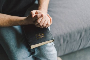 Hristiyan adam kutsal İncil 'i elinde tutuyor. Bir evde İncil 'i okumak. İnanç, maneviyat ve din kavramı. Barış, umut