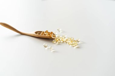 Beyaz arka planda vitaminler. Kaşık üzerindeki kapsüller: balık yağı, omega 3, omega 6, omega 9, A vitamini, D vitamini, D3 vitamini, E vitamini konsepti.