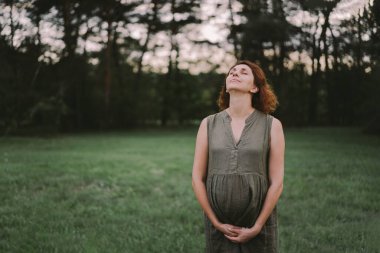 Güzel hamile bir kadın dışarıda, mutlu bir bebek bekliyor ve mutlu bir hamilelik dönemi geçiriyor. Hamilelik ve aile kavramları. Annelik. Hamile karnı. Bebek bekliyor.