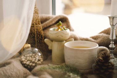 Noel kompozisyonu. Sıcak çay, mumlar, Noel altın topları ve süslemeler. Noel tatili havası. Kış konsepti.