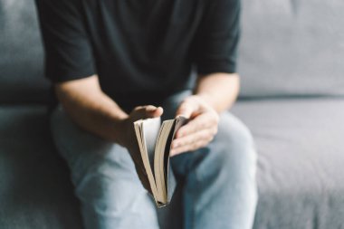 Hristiyan adam kutsal İncil 'i elinde tutuyor. Bir evde İncil 'i okumak. İnanç, maneviyat ve din kavramı. Barış, umut