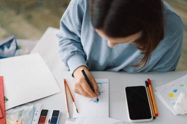 Genç kız, Kardan Adam 'la renkli kâğıt başvurusu yapıyor. Yaratıcılık kavramı. Kız el işi, kartpostal, kağıt, yaratıcılık için çok renkli kağıtlar yapıyor. Evden çalışıyorum. Hobi