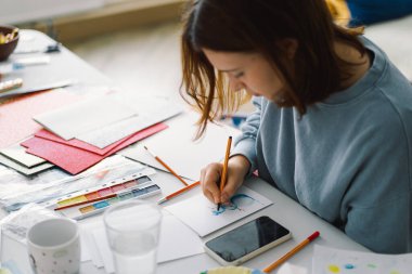 Genç kız, Kardan Adam 'la renkli kâğıt başvurusu yapıyor. Yaratıcılık kavramı. Kız el işi, kartpostal, kağıt, yaratıcılık için çok renkli kağıtlar yapıyor. Evden çalışıyorum. Hobi