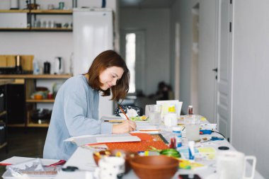 Genç kız, Kardan Adam 'la renkli kâğıt başvurusu yapıyor. Yaratıcılık kavramı. Kız el işi, kartpostal, kağıt, yaratıcılık için çok renkli kağıtlar yapıyor. Evden çalışıyorum. Hobi