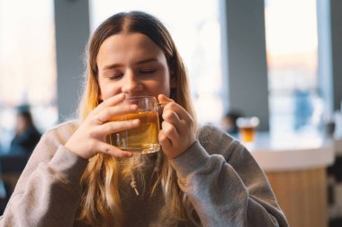 Kafede çay içen neşeli bir genç kızın portresi. Gülümseyen güzel kız kışın sıcak çay içer. Genç kız sıcak çay içiyor. Cafe City yaşam tarzı. Mutlu güzel kızın renkli portresi