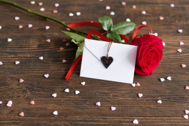 Red rose with postcard on wooden background. Happy Valentines Day postcard. Love concept for mothers day or valentines day. Valentine card with space for text