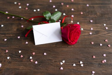 Red rose with postcard on wooden background. Happy Valentines Day postcard. Love concept for mothers day or valentines day. Valentine card with space for text