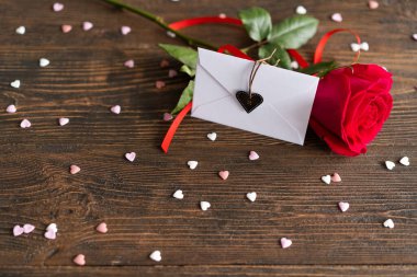 Red rose with postcard on wooden background. Happy Valentines Day postcard. Love concept for mothers day or valentines day. Valentine card with space for text
