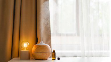 Aromatherapy concept. Aroma oil diffuser on the table against the window. Air freshener. Ultrasonic aroma diffuser for home