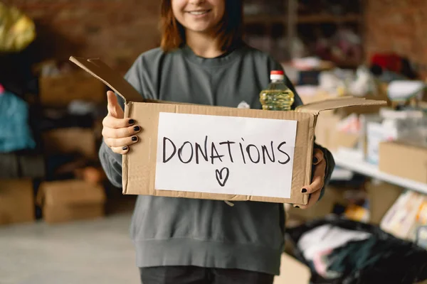 Volunteer teengirl preparing donation boxes for people. Donation clothing for refugees, support of war victims. Humanitarian aid concept.Helping people