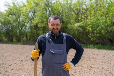 a man planting potatoes in the ground in early spring. Farmer with a shovel