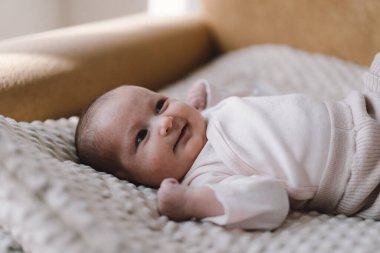 Portrait of a 1 month old baby. Cute newborn baby lying on a developing rug. Love baby. Newborn baby and mother.