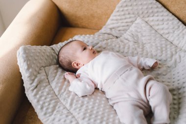 Portrait of a 1 month old baby. Cute newborn baby lying on a developing rug. Love baby. Newborn baby and mother.
