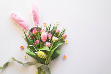 Happy Easter. Stylish dyed easter eggs with spring flowers on white background. Pink tulips with colorful eggs