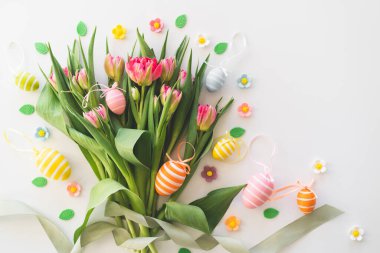 Happy Easter. Stylish dyed easter eggs with spring flowers on white background. Pink tulips with colorful eggs