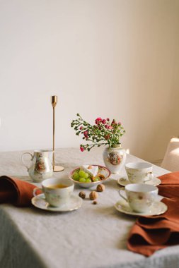 Vintage table setting with Linen napkins and floral decorations. Close up. Cozy calm meal in the morning in the sunshine.