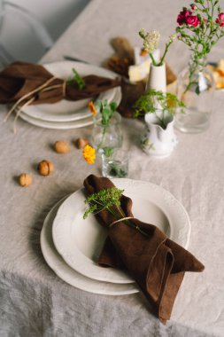 Vintage table setting with Linen napkins and floral decorations. Close up. Cozy calm meal in the morning in the sunshine.