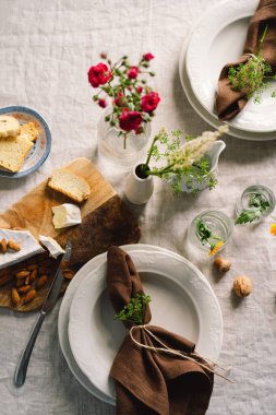 Vintage table setting with Linen napkins and floral decorations. Close up. Cozy calm meal in the morning in the sunshine.