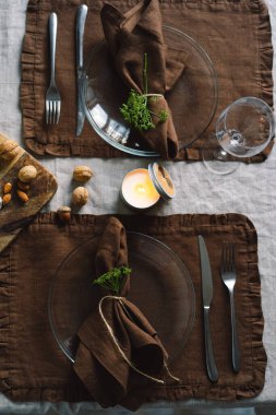 Vintage table setting with Linen napkins and floral decorations. Close up. Cozy calm meal in the morning in the sunshine.