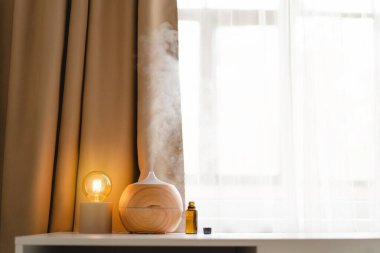 Aromatherapy concept. Aroma oil diffuser on the table against the window. Air freshener. Ultrasonic aroma diffuser for home