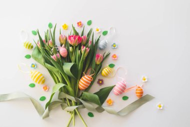 Happy Easter. Stylish dyed easter eggs with spring flowers on white background. Pink tulips with colorful eggs