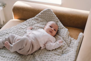 Portrait of a 1 month old baby. Cute newborn baby lying on a developing rug. Love baby. Newborn baby and mother.
