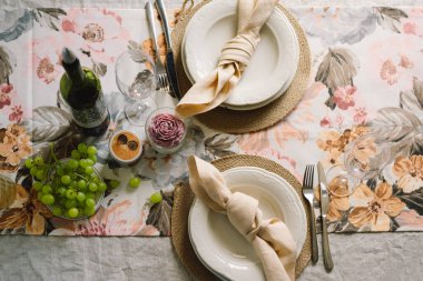 Vintage table setting with Linen napkins and floral decorations. Close up. Cozy calm meal in the morning in the sunshine.