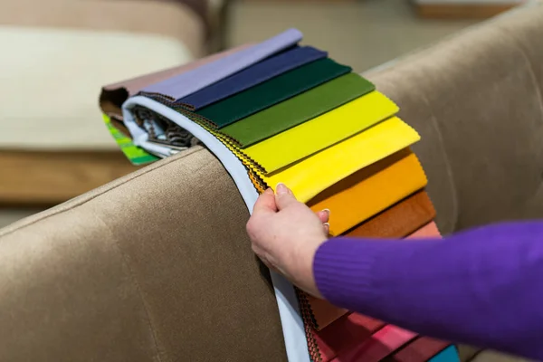 The woman chooses the fabric on the sofa. A women looks at tissue samples. Selects the color of the sofa. Textile industry background. Tissue catalog