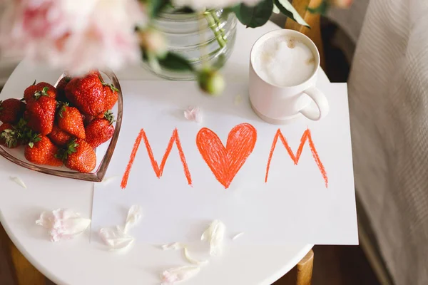 母亲节早餐 心形白盘 有新鲜草莓 一杯咖啡 礼物和牡丹的花束 还有床上的礼物 静止不动的生活构成 母亲节快乐 — 图库照片