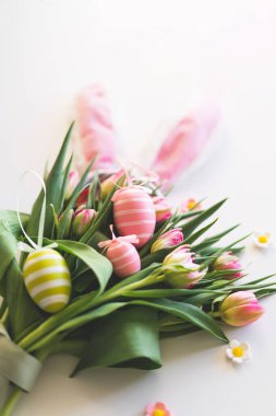 Happy Easter. Stylish dyed easter eggs with spring flowers on white background. Pink tulips with colorful eggs