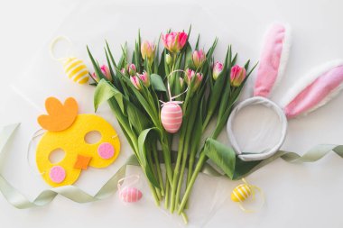 Happy Easter. Stylish dyed easter eggs with spring flowers on white background. Pink tulips with colorful eggs