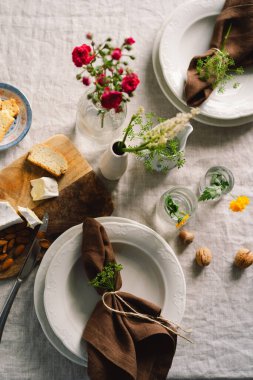 Vintage table setting with Linen napkins and floral decorations. Close up. Cozy calm meal in the morning in the sunshine.