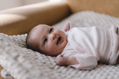 Portrait of a 1 month old baby. Cute newborn baby lying on a developing rug. Love baby. Newborn baby and mother.