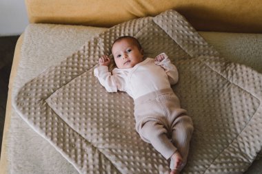 Portrait of a 1 month old baby. Cute newborn baby lying on a developing rug. Love baby. Newborn baby and mother.
