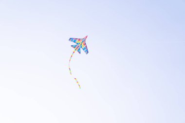 Mavi gökyüzüne uçan renkli bir uçurtma. Bulutların arasında uçan uçurtma