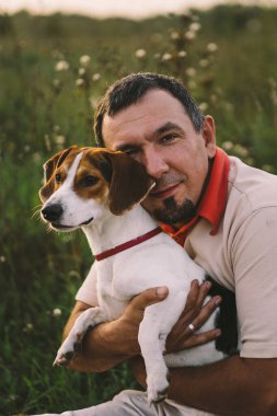 Parkta Jack Russell köpeğiyle oynayan bir adamın portresi. Hayvanlar, arkadaşlık, insanlar ve aşk kavramı. Adamın biri Jack Russell Terrier ile oynuyor.