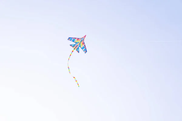 A color kite flying against a blue sky. Kite flying in the sky among the clouds