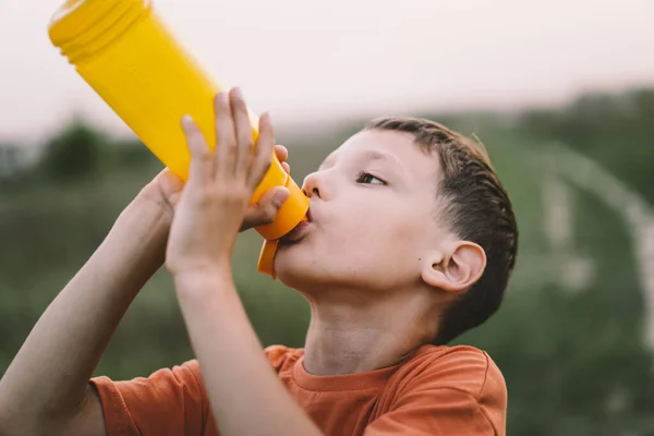 Bambino Beve Acqua Una Bottiglia Arancione Mentre Cammina Salute Del — Foto Stock