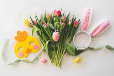 Happy Easter. Stylish dyed easter eggs with spring flowers on white background. Pink tulips with colorful eggs