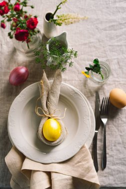 Happy Easter. Stylish easter eggs on a napkin with spring flowers on white wooden background. Table setting. The concept of a happy Easter holiday.