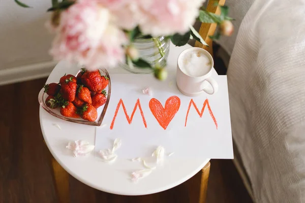 母亲节早餐 心形白盘 有新鲜草莓 一杯咖啡 礼物和牡丹的花束 还有床上的礼物 静止不动的生活构成 母亲节快乐 — 图库照片