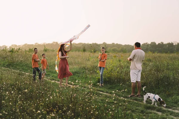 stock image Happy family and children run on meadow with a kite in the summer on the nature. Family playing with kite while running along rural summer field. Family day