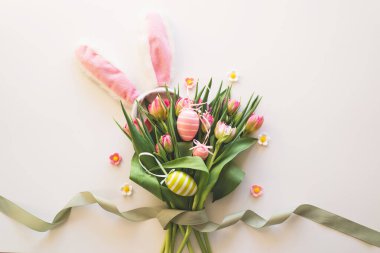 Happy Easter. Stylish dyed easter eggs with spring flowers on white background. Pink tulips with colorful eggs