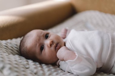 Portrait of a 1 month old baby. Cute newborn baby lying on a developing rug. Love baby. Newborn baby and mother.