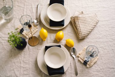 Vintage table setting with Linen napkins and yellow lemons. Decoration table. Close up. Cozy calm meal in the morning in the sunshine.