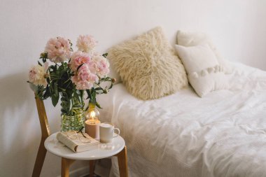 Still life details in home interior of living room. Open book with glasses, cup coffee and bouquet white pink peonies flowers. Read and rest. Cozy home clipart